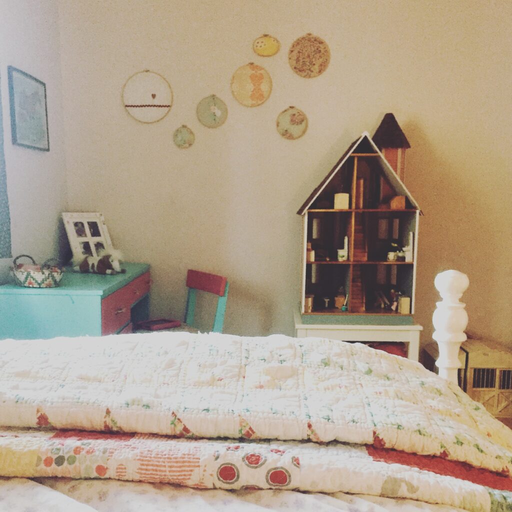girls bedroom with quilts and dollhouse