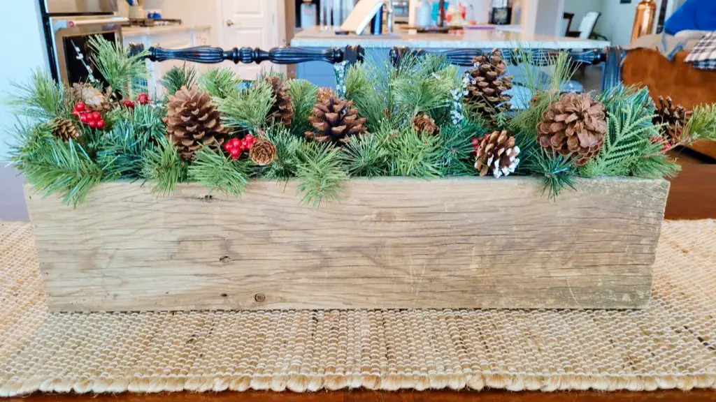 pinecones and evergreen boughs in wooden box on table