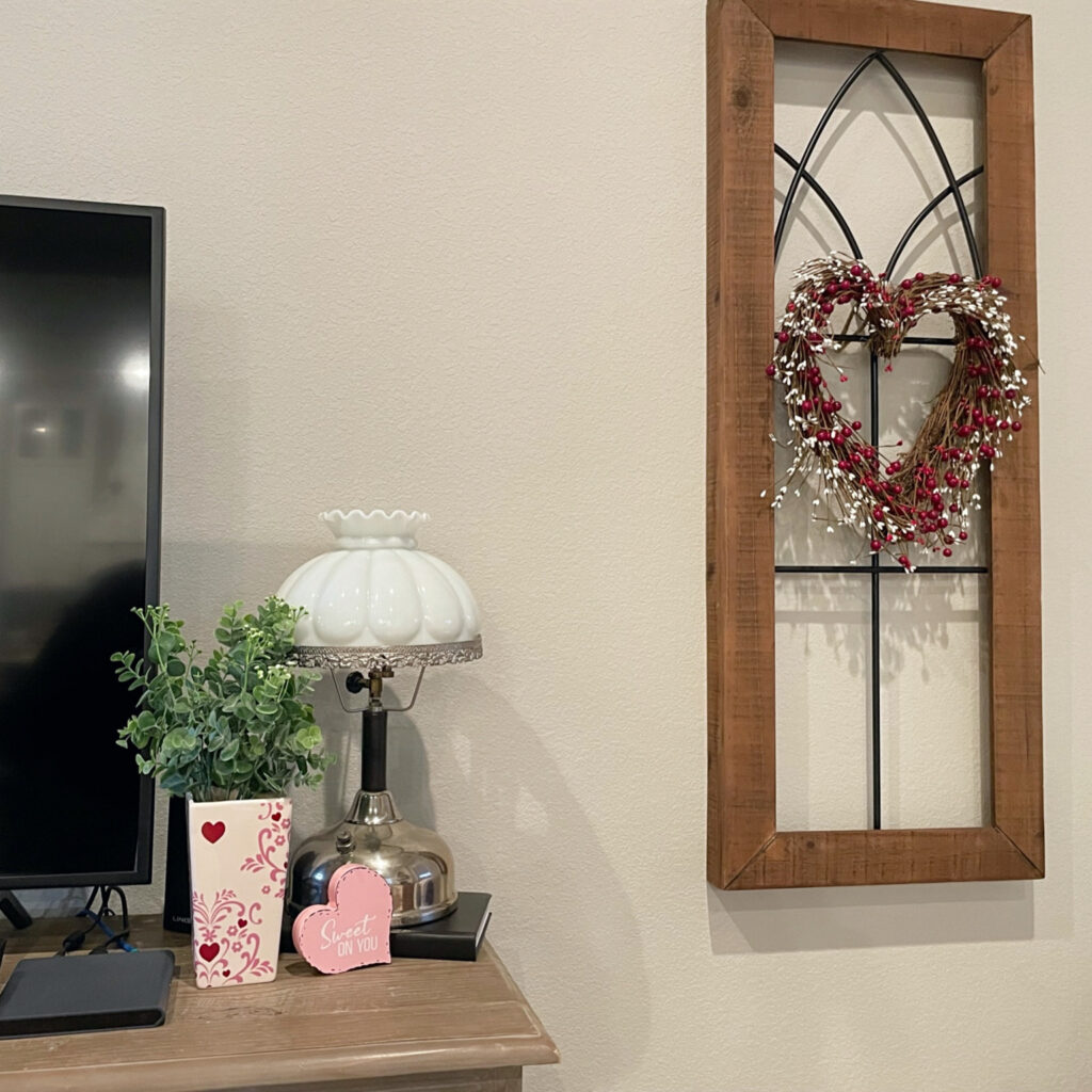 wood and wrought iron wall hanging with a heart shaped wreath with red and pink beads