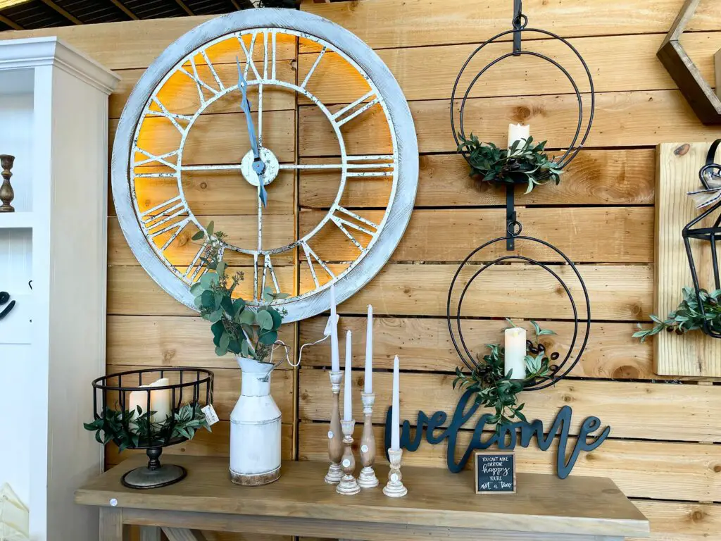 Large white clock accented with black pieces and wooden candle sticks.