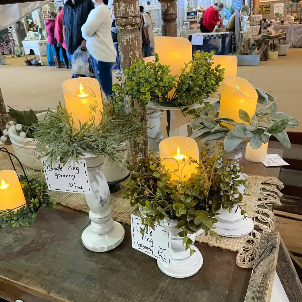 White candlesticks with greenery wreaths and candles