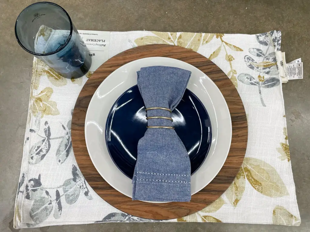 Blue, white, and yellow table setting with a stunning wooden charger