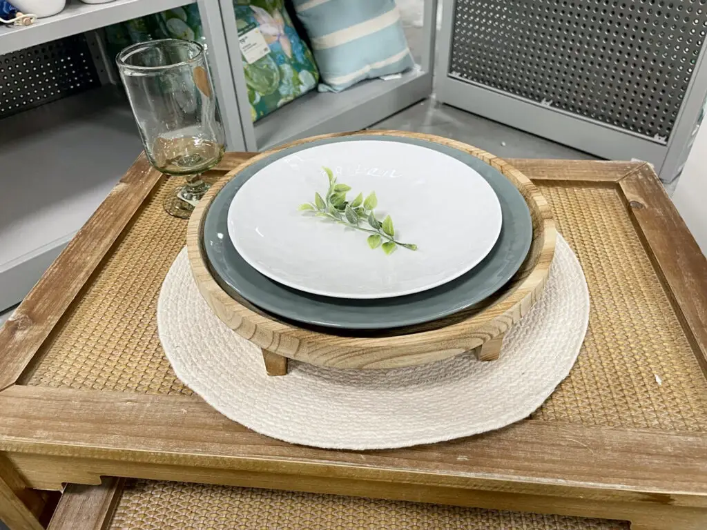 Lifted natural wood tray charger with green and white plates.