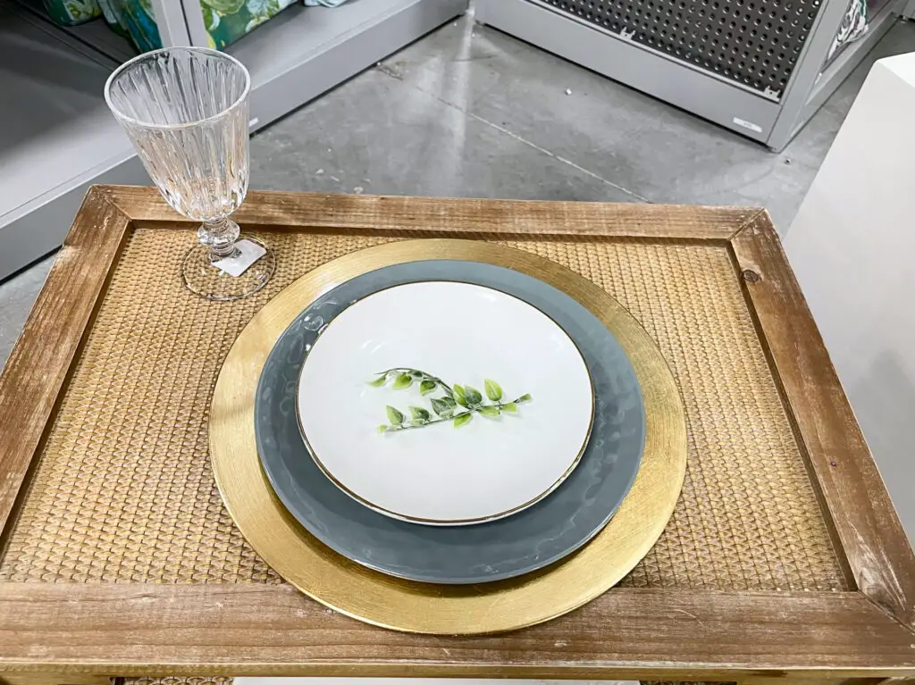 Gold charger with grey and white plates topped with a small greenery stem