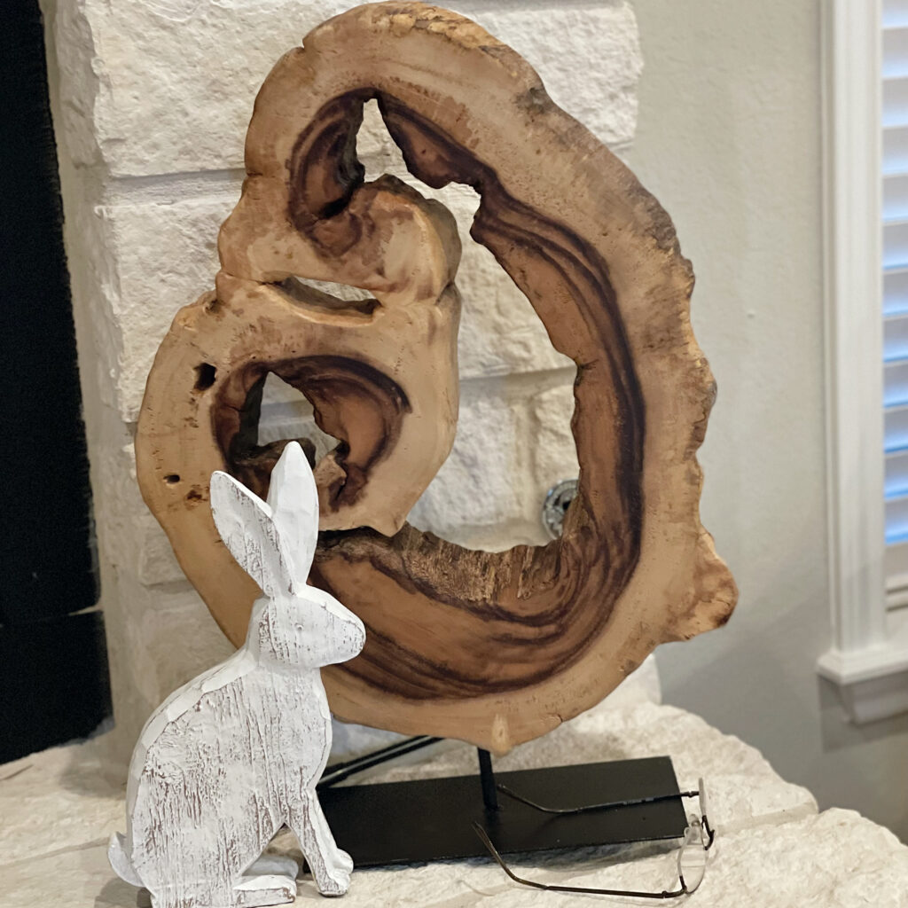 White bunny in front of tree stump wood sculpture