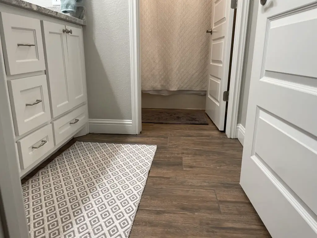 Grey and white rugs in front of the vanity and the bathtub