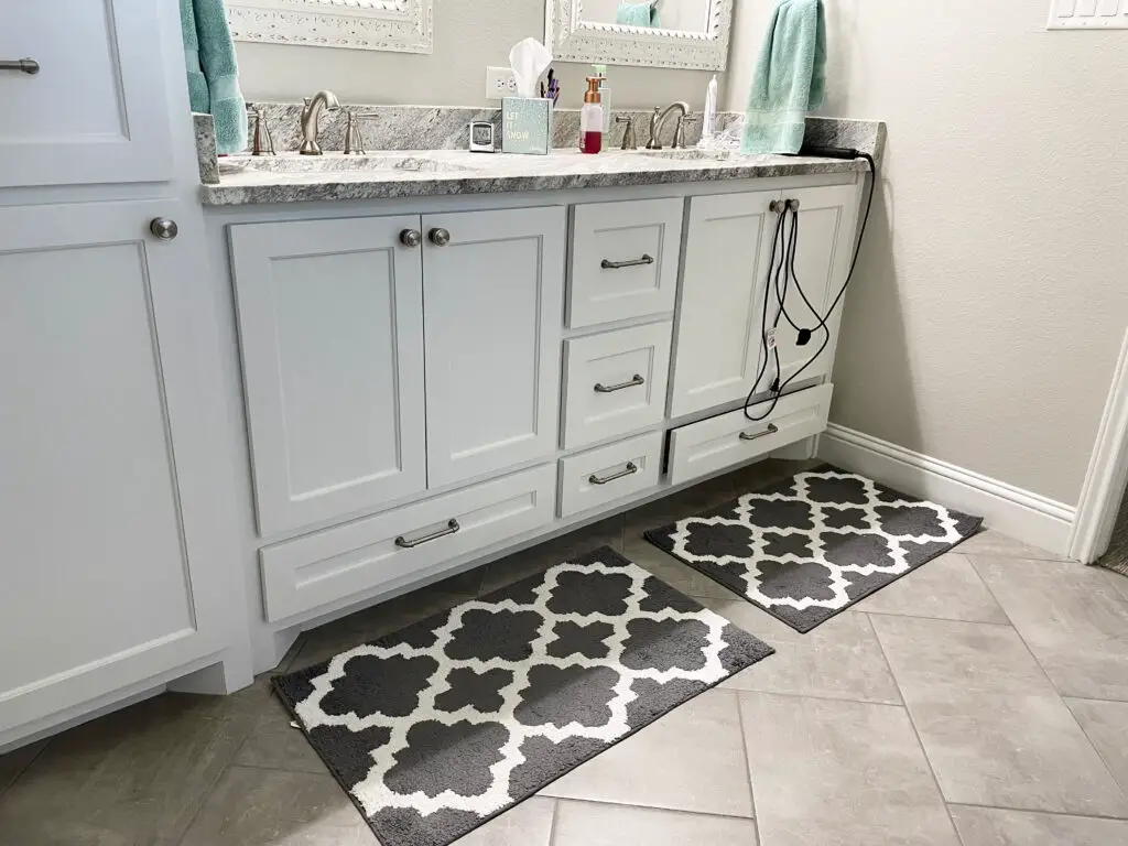 grey and white patterned rugs in front of a white master vanity