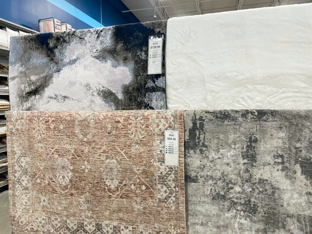 4 vastly different rugs hung on a store display.