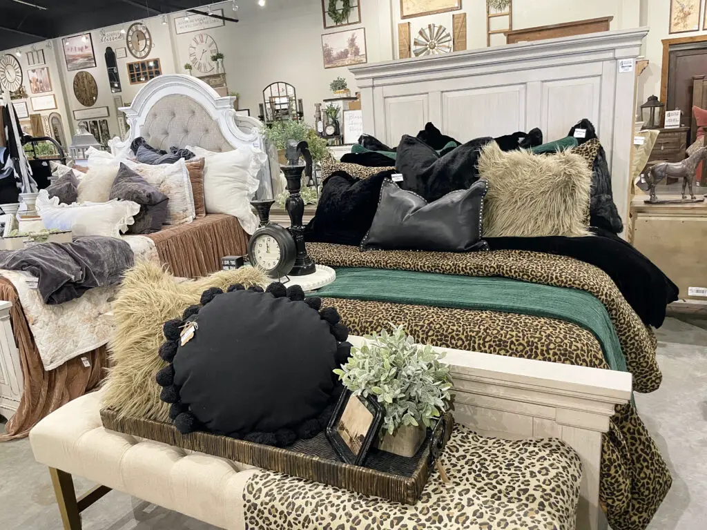 Cheetah print, black, and green bedding on a white washed farmhouse bed frame