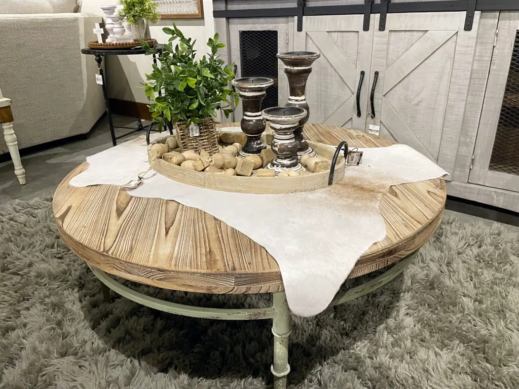 light wood coffee table with hide rug overlay under a tray of decorations