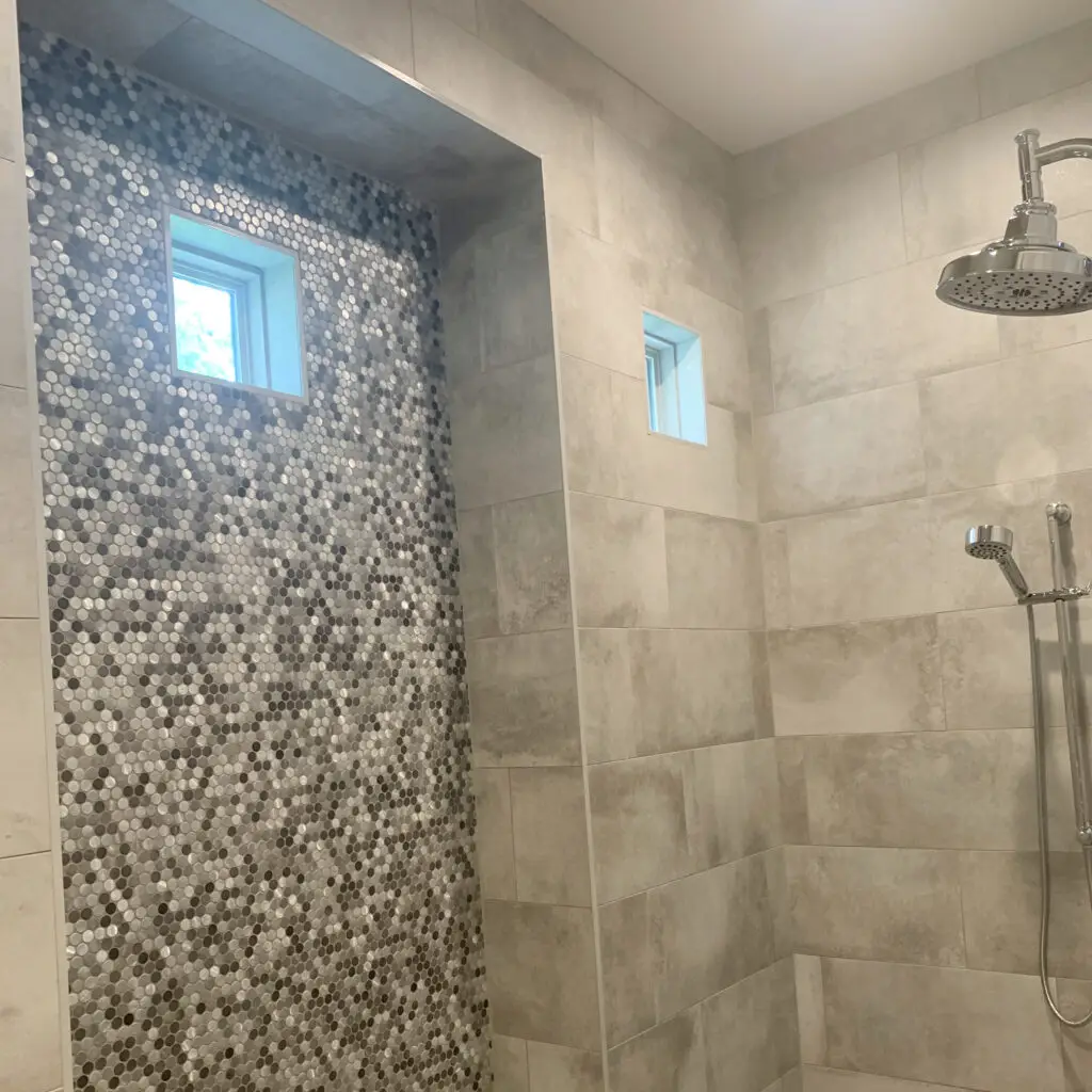 Grey tile, with grey hued penny tile cutout and chrome shower fixtures