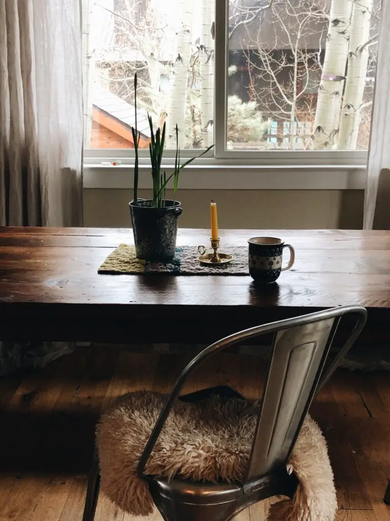 dining table with mug and candle in front of window