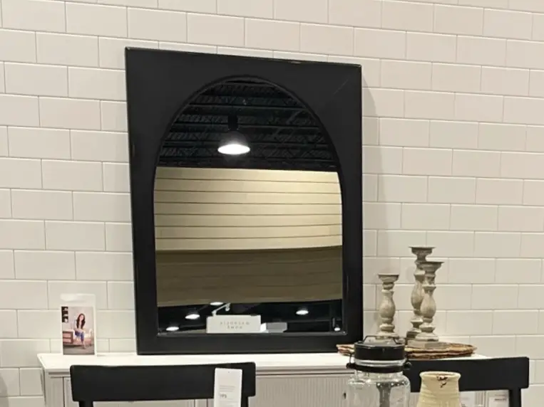 Black mirror over white sideboard with organic decor accents