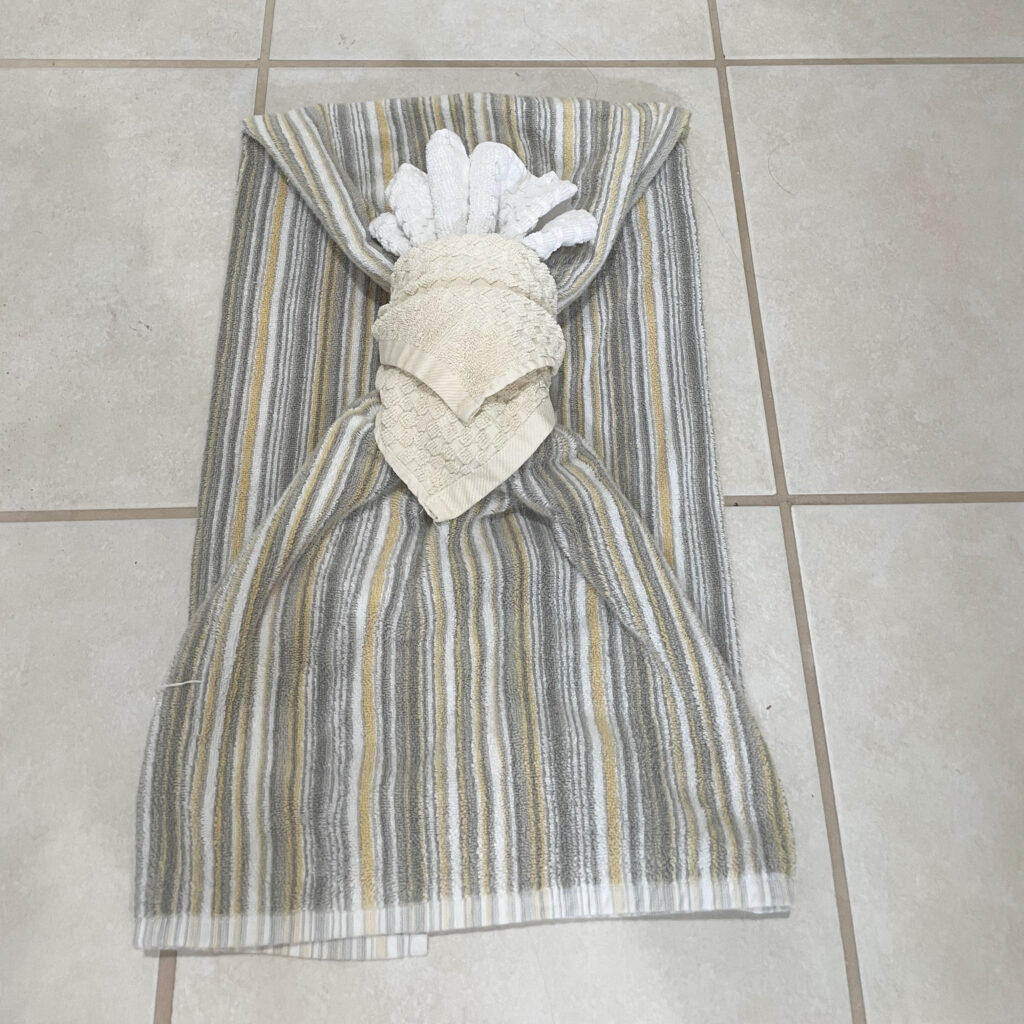 Yellow, grey and white striped towel with a yellow and white wash cloth wrapped around the middle