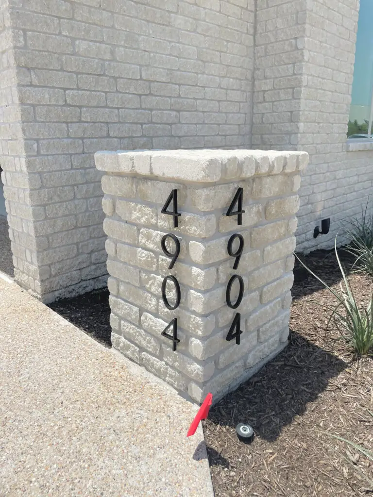 White brick post with house numbers on either side.