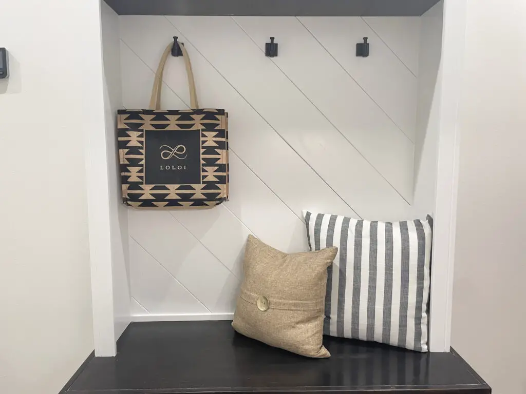 White mudroom bench with diagonal slats and grey and tan accents
