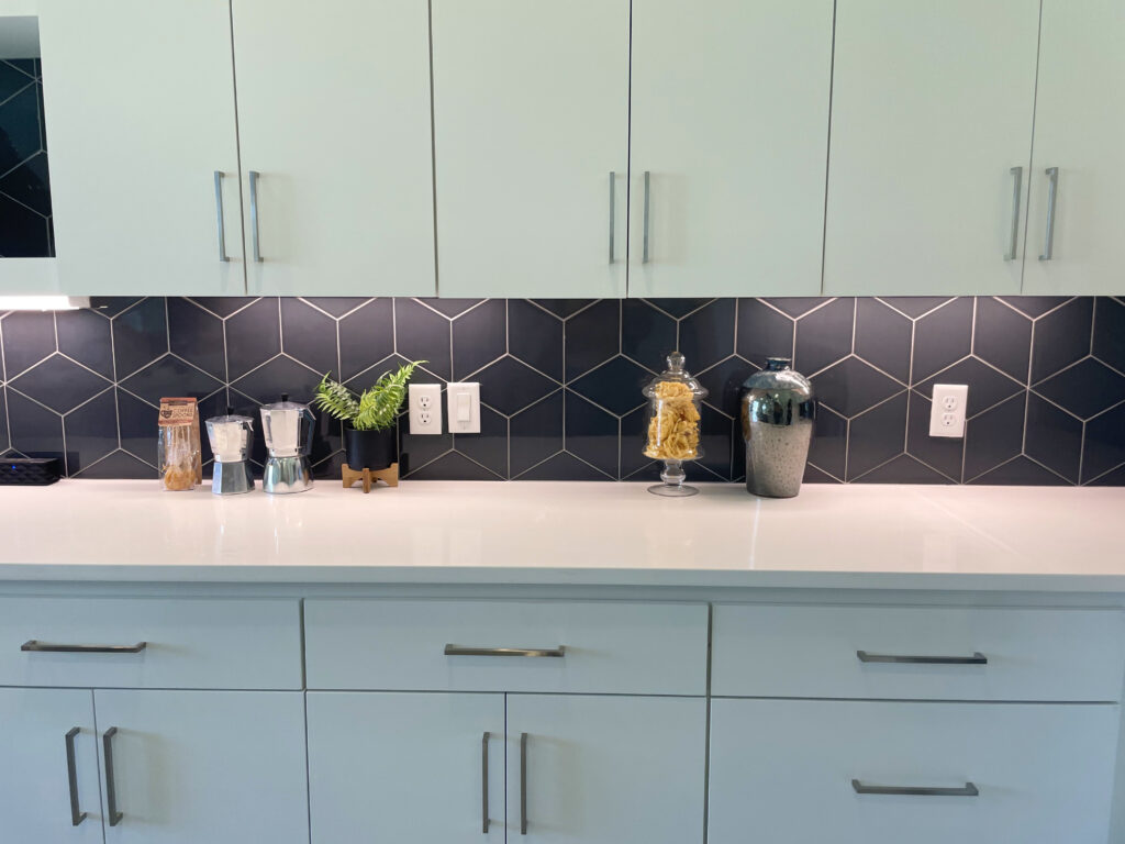 Pale green cabinets with black backsplash and modern accents