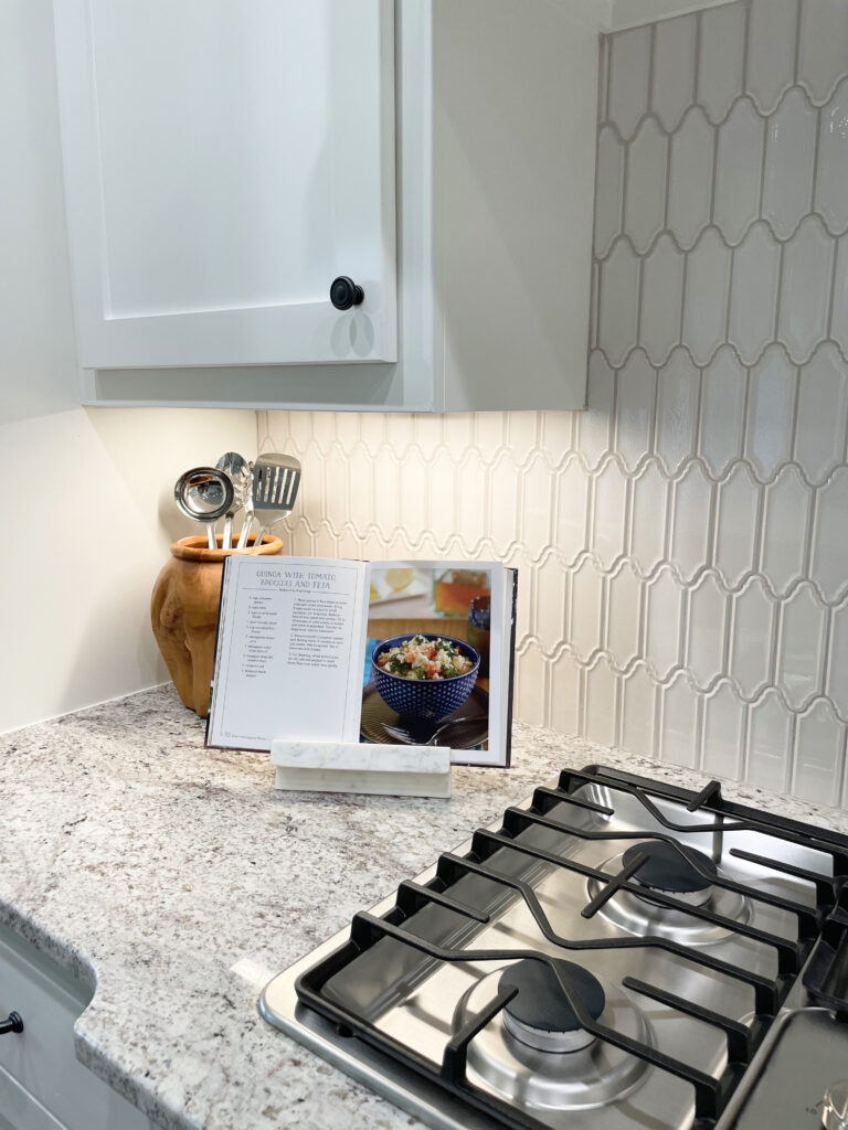Cookbook held open on marble holder in white and grey kitchen