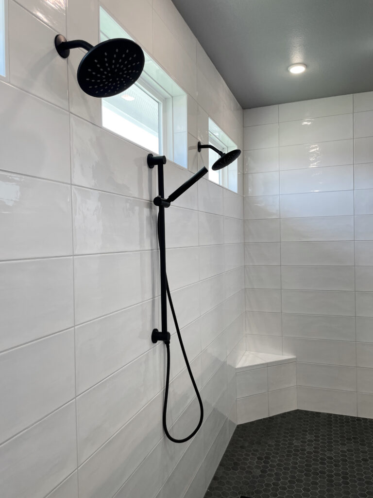 dual black shower heads in large walk in shower with white tile