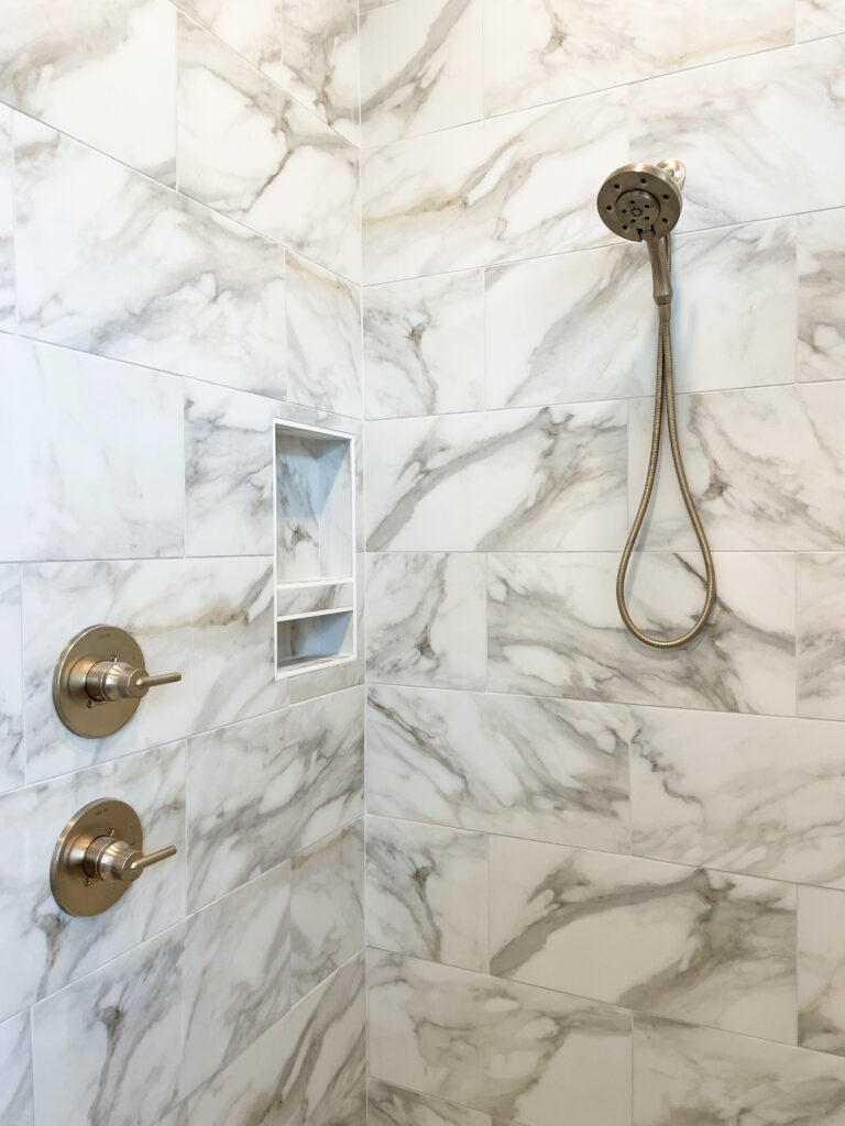 White and grey marbled, large scale shower tile with gold accents
