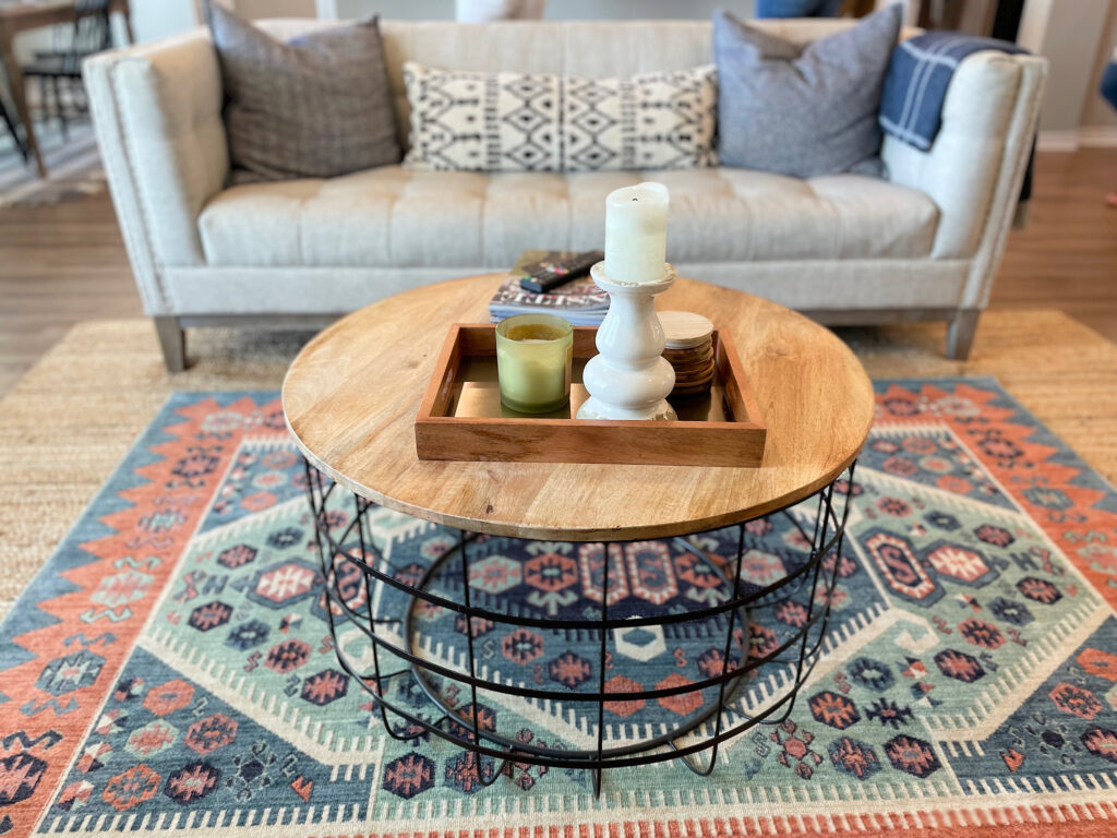 Basket coffee table with neutral candle decor in wooden tray