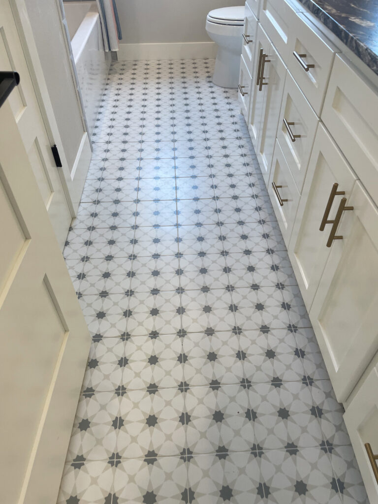 star-like pattern of greys on the tile flooring of an elongated bathroom