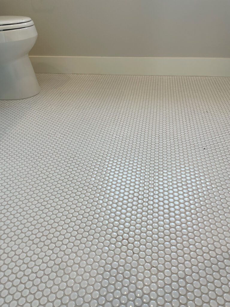 White penny tile flooring with grey grout in a bathroom
