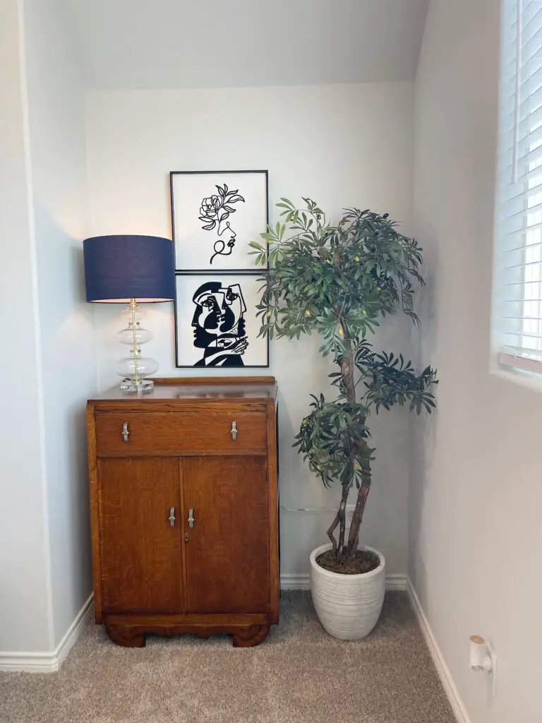 Wooden dresser with blue lamp next to tall plant neatly designing an awkward corner