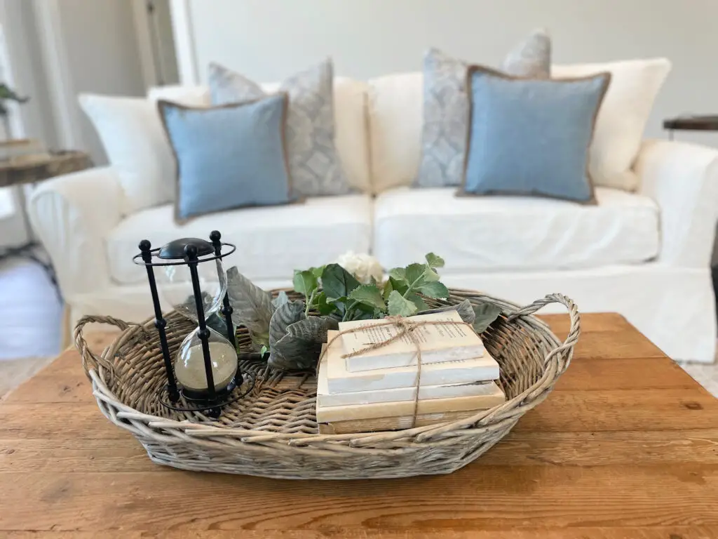 Grey wicker trey with modern farmhouse decorative accents on coffee table