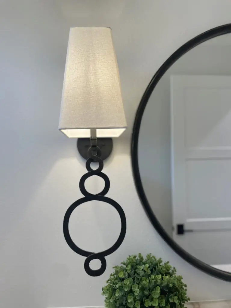 Traditional wall sconce with long loop details at the tale and a square shade at the top