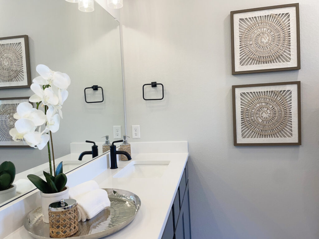 White and grey bathroom with tray filled with towels, storage container, and potted orchid