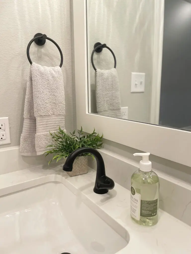 All white bathroom with green and grey decorative accents on the bathroom counter