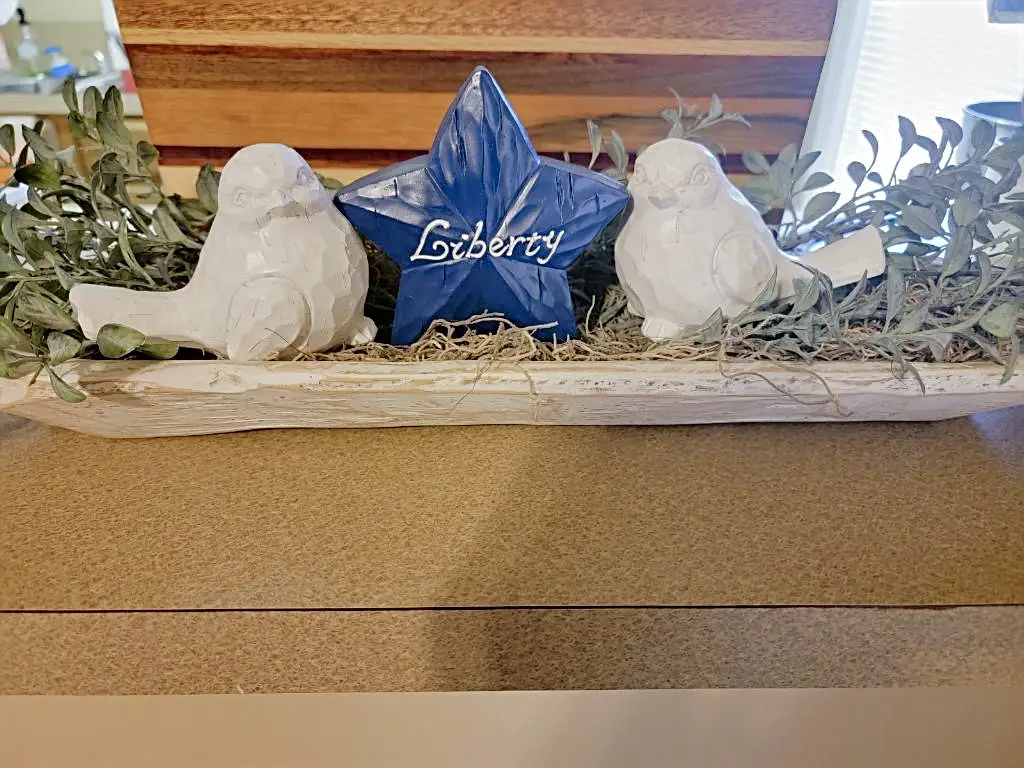 white dough bowl with greenery, two white birds, and a bold blue star