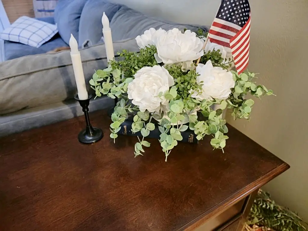 American flag placed in decorative bouquet on sideboard next to a couple of candlesticks