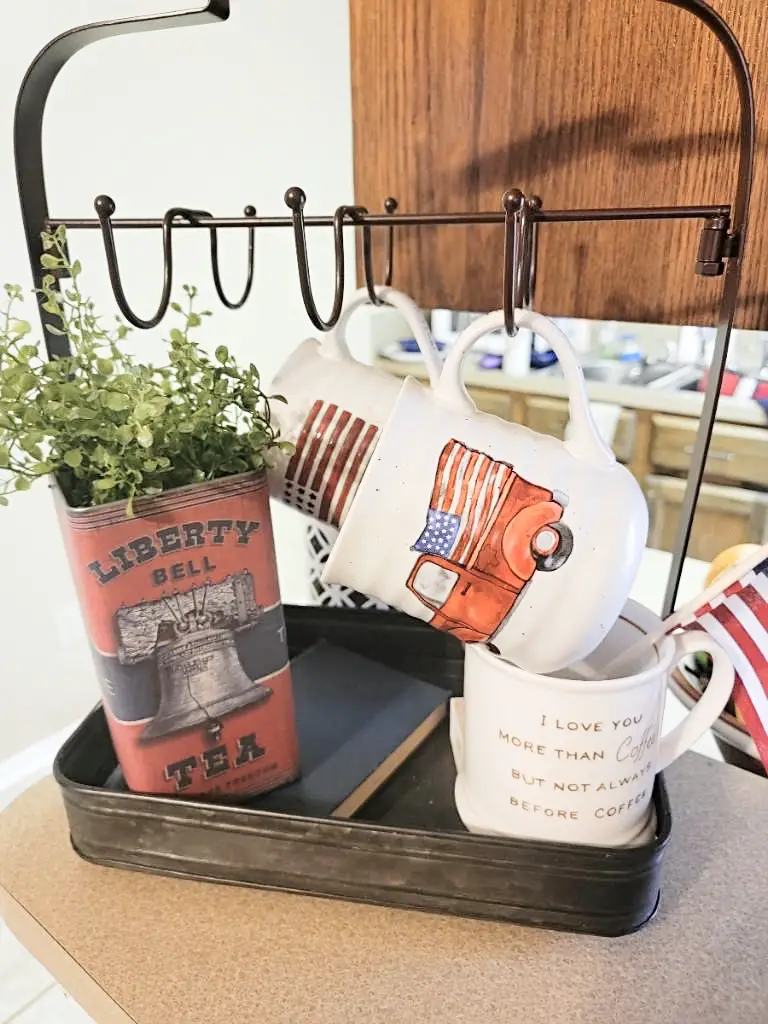 Red, white, and blue coffee mugs in mug hanger with holiday themed decorative accents & greens