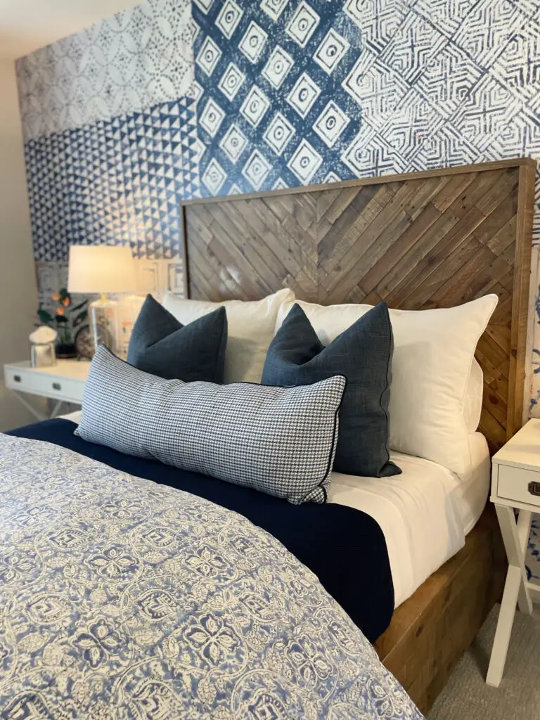 Blue and white bedding with white side tables next to chevron patterned natural wood headboard & bed frame