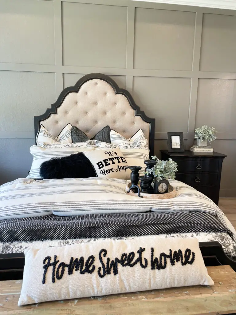 Greige board and batten wall with black wooden farmhouse headboard and cream tufted fabric adorned with black, grey and cream bedding