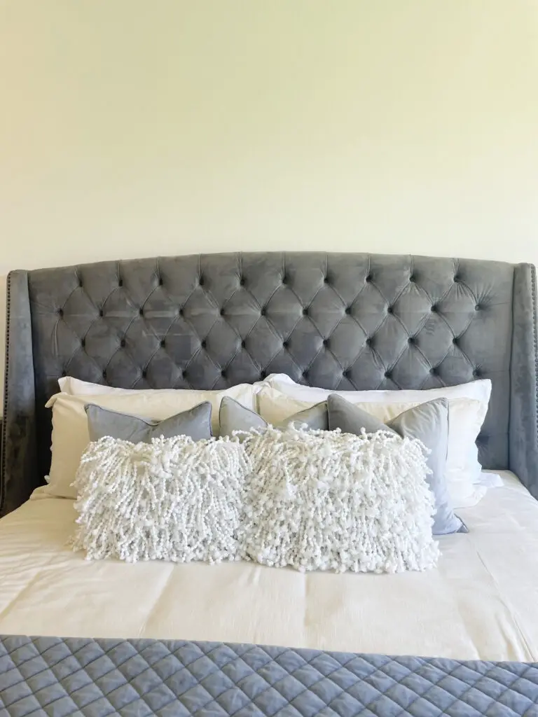 Grey, tufted velvet headboard with white and grey throw pillows