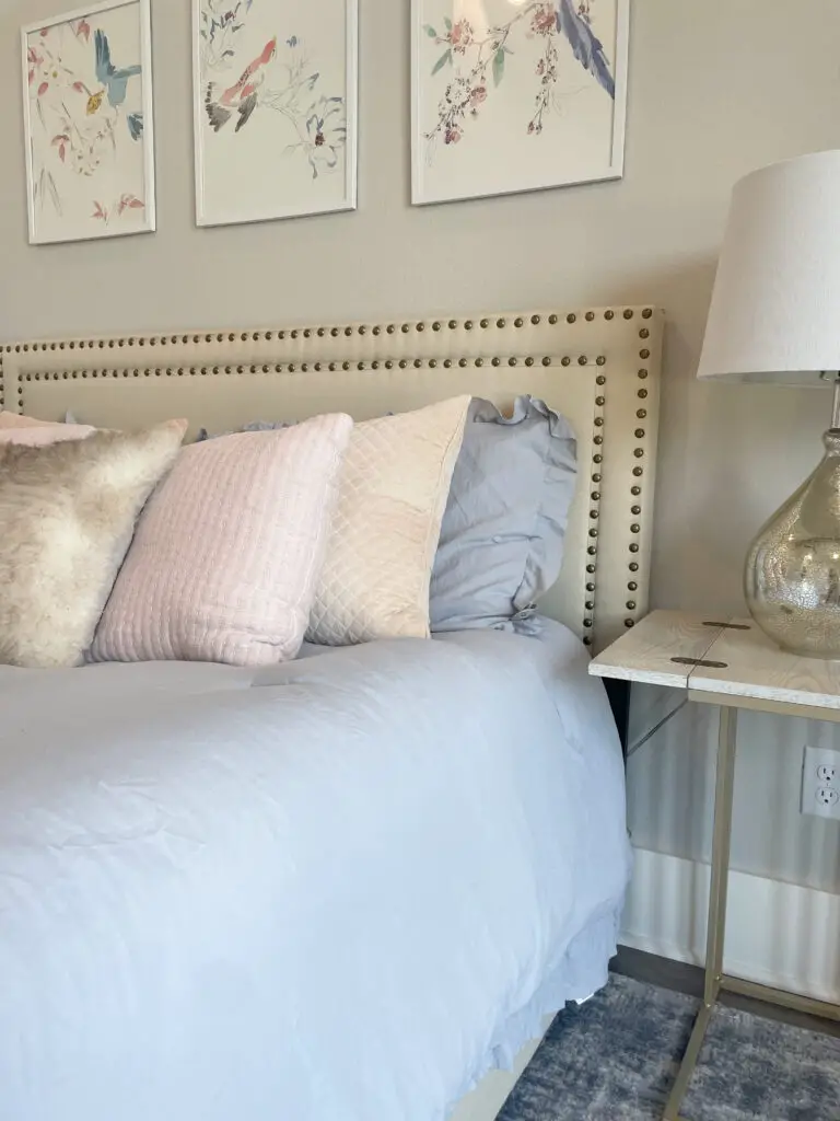 Creme fabric headboard with brushed bronze studs and pink & blue French country style bedding and accents