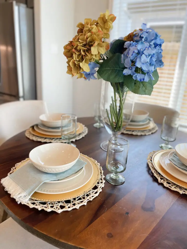 Blue & yellow flowers with tablescape with dishes, napkins, and cups