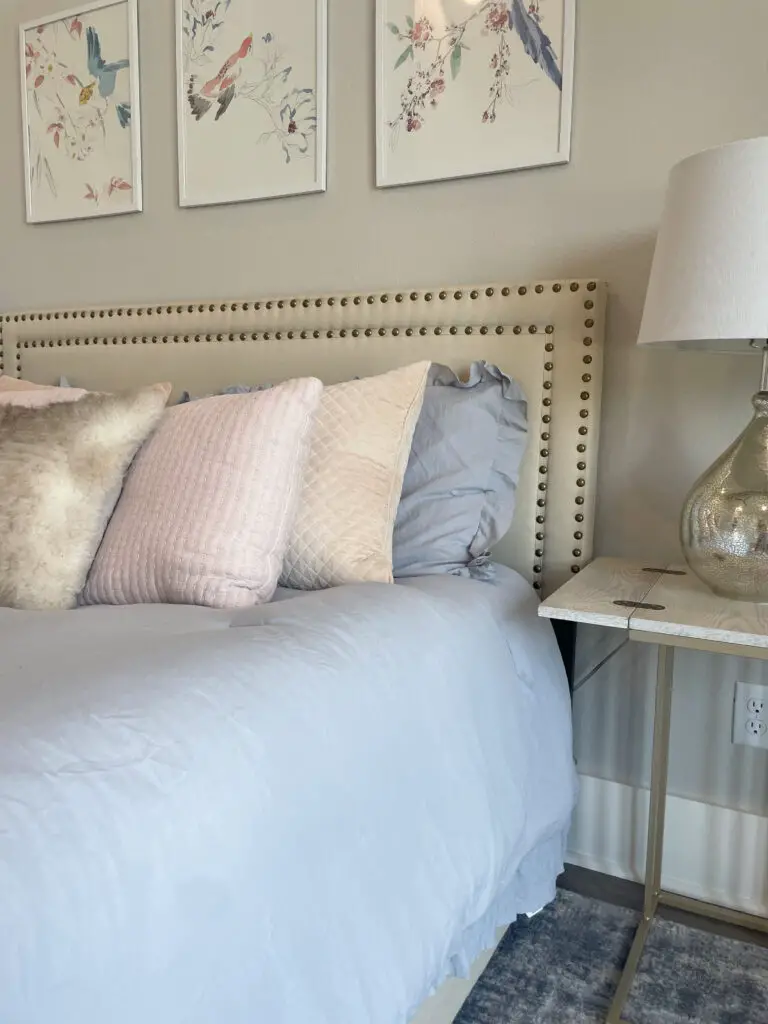 Blue, white, and pink layers of pillows on a cozy bed