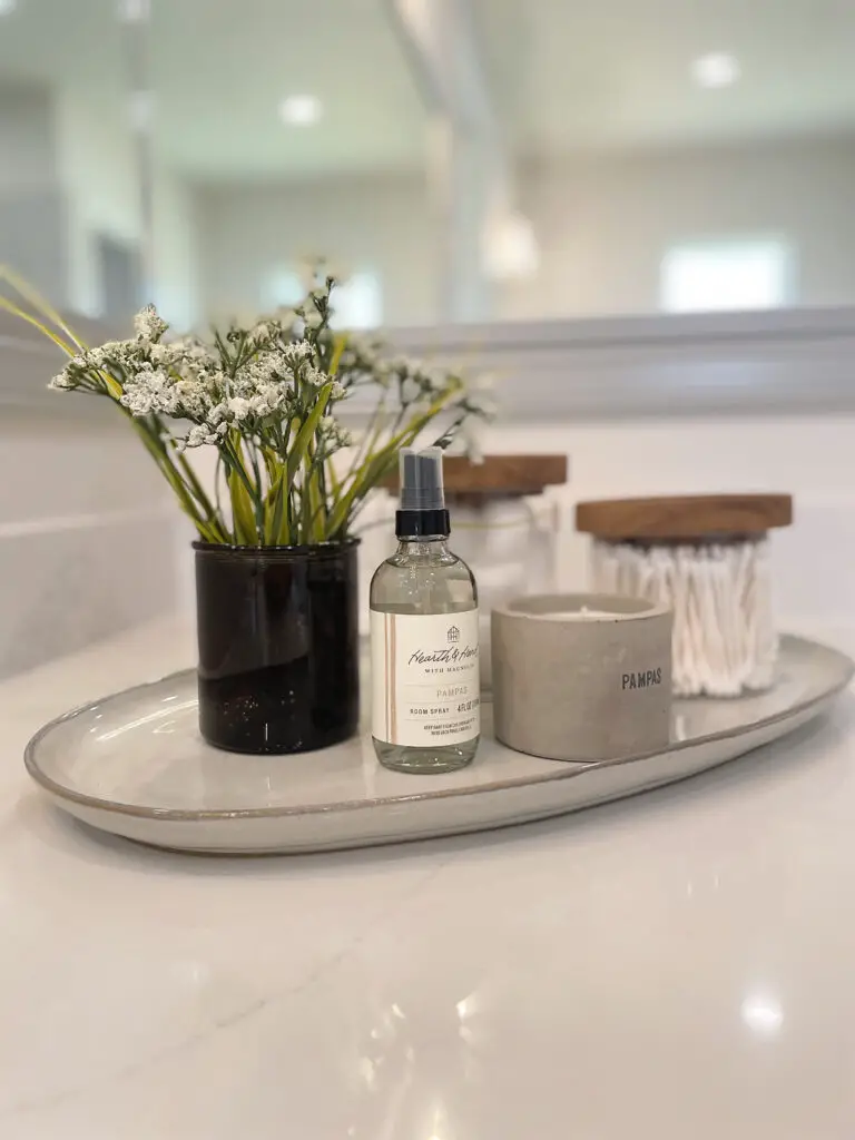Cozy home bathroom tray with white flowers in a shaded black vase with wooden and concrete accents
