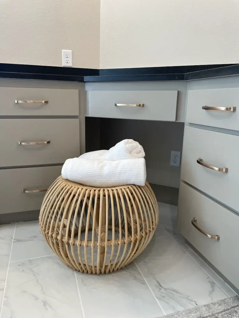 Two white towels rolled up on bamboo vanity stool