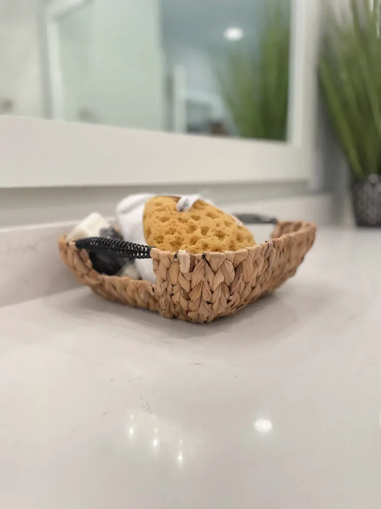 Wicker basket with sponge, towel and soap on bathroom counter