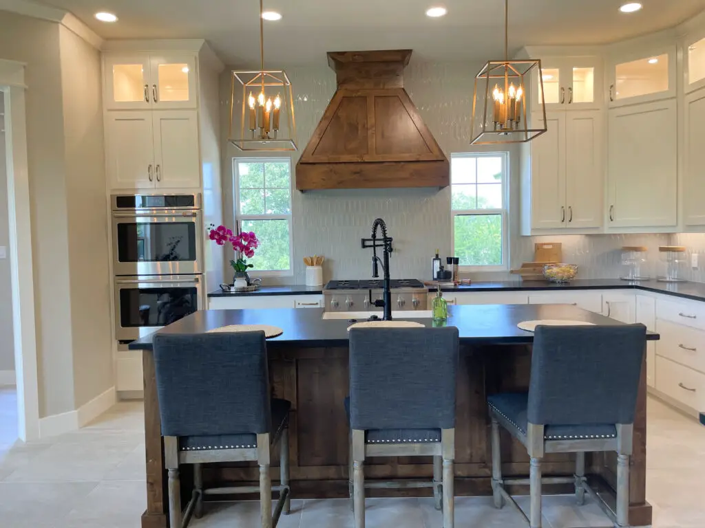 white cabinets with a wooden island and 3 grey, fabric barstools
