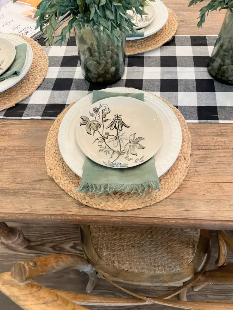 Green, white, and tan dishes with a green napkin on a wicker, rope placemat