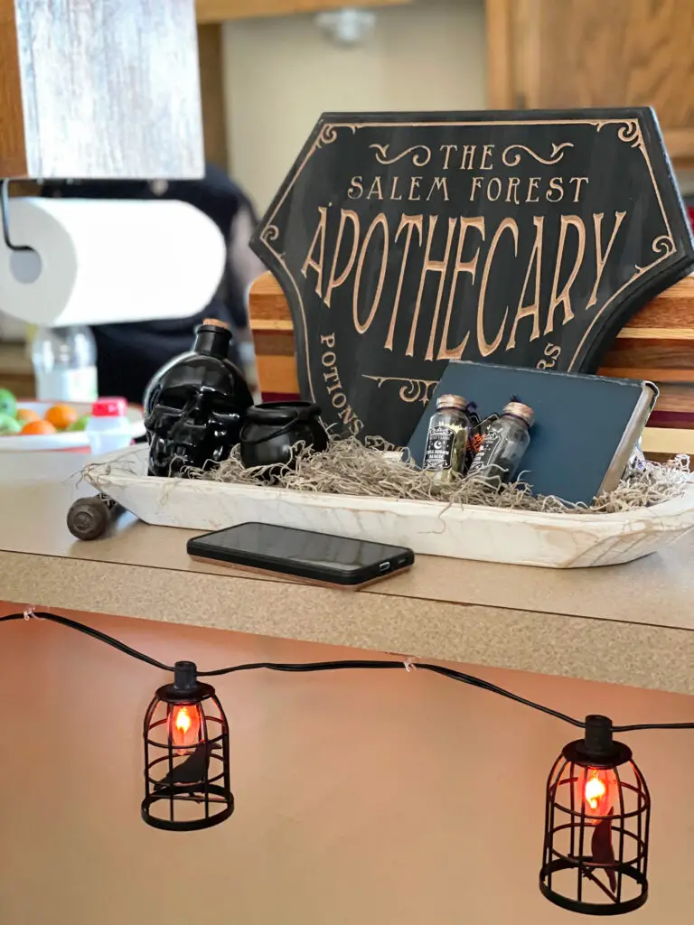Halloween potion decorations in a dough bowl on the kitchen island with  spooky lanterns hung off the edge
