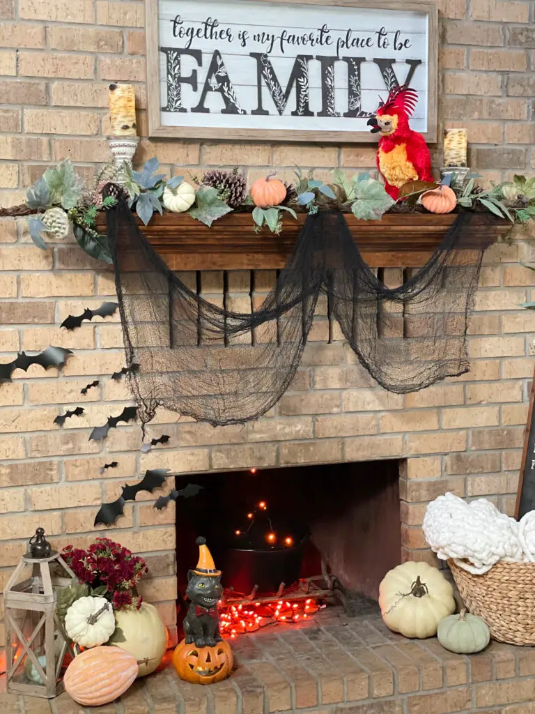 Pumpkins and Halloween decor adorning the fireplace which houses a cauldron with fun string lights