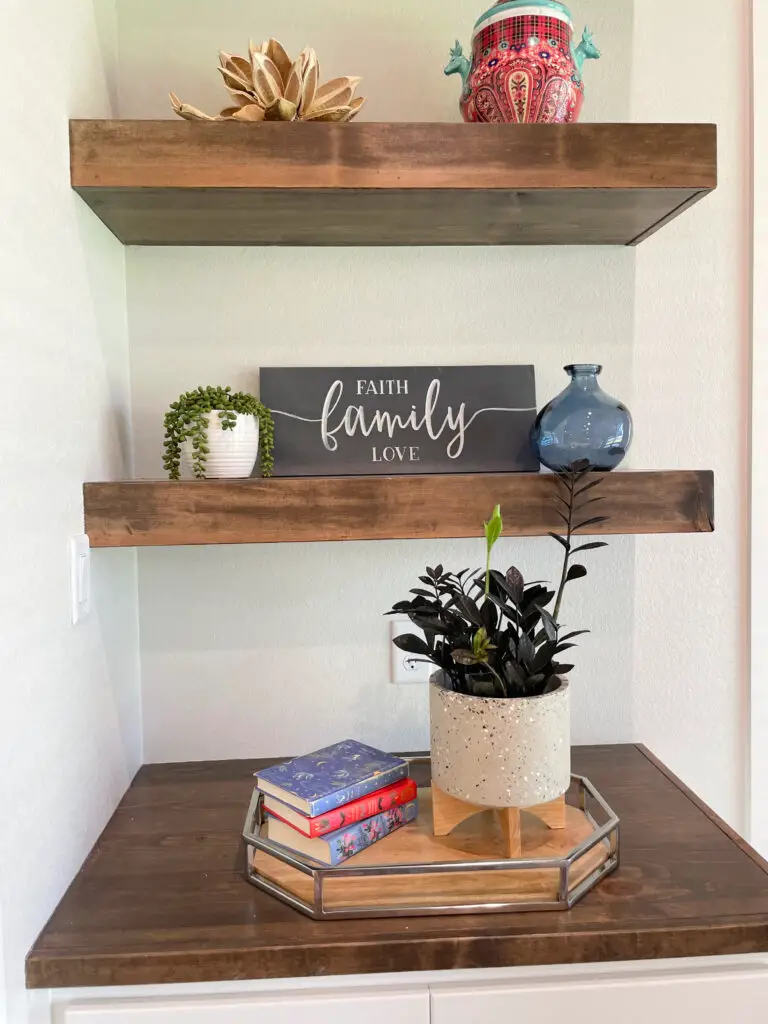 Square shelves with wicker baskets in the holes and antique decorative pieces on top surrounding a chalk board