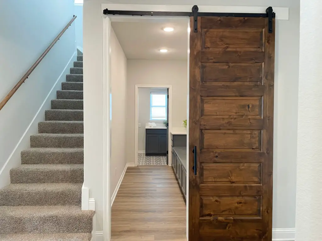 barn door that leads into narrow mudroom connected to grey laundry room